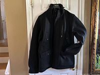 Front view of black Zara Man wool coat on hanger showing overall condition and style