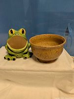 Front view of frog figurine and stoneware bowl together