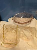 Large pink depression glass bowl with etched floral design and two smaller matching pieces
