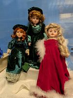 Full view of three porcelain dolls showing outfits and relative sizes
