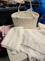 overview of basket with assorted lace linens, pink gingham cloth and beige napkins