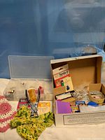 Overview of lot showing organizer, pliers, crochet pieces, cardboard box of supplies