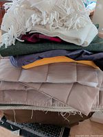 Stack of assorted fabrics showing fringe fleece, multiple colored fabrics and quilted padding