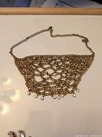 Overall view of gold-tone mesh bib necklace with rhinestone fringe