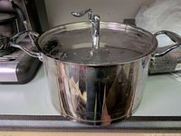 Side view of stainless steel pot with lid and handles