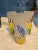 three frosted glasses showing heron and cattail graphics