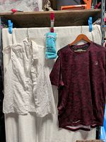 Overall view of all three items: white sleeveless blouse, maroon heather AND1 tee, sealed blue mittens