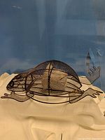 Side profile of wire mesh frog candle holder with candle inside