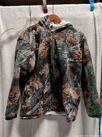 Front view of hooded camouflage jacket on hanger