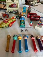 Group shot of all tin toys, model buses, figures and PEZ dispensers displayed on table