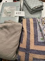 All bedding items including packaged sheet set, grey check duvet pieces, beige quilted coverlet, multicolour embroidered coverlet