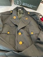 Front view of US Army dress jacket showing buttons, pockets and shoulder insignia; ammo boxes partially visible