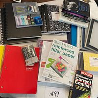Overview of lot showing notebooks, filler paper, push pins, cap erasers, binders, frame, composition books and stack of books