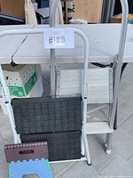 Front view of three folded step ladders leaning against table