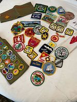 Overall view of garrison cap, merit badge sash and assortment of loose Boy Scout patches on table