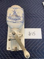 Full view of wall-mount coffee grinder showing porcelain hopper, metal crank, glass jar