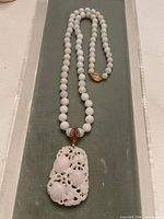 Full view of white jade beaded necklace showing pendant and gold clasp