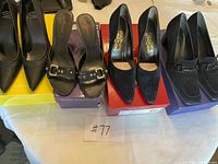 Wide shot of four pairs of black women’s shoes on boxes