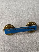 Front view of blue enamel rifle marksmanship bar pin with clutches attached
