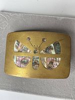 Front view of brass belt buckle with abalone inlay design