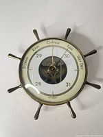 Front view of brass ship-wheel barometer showing dial and spokes