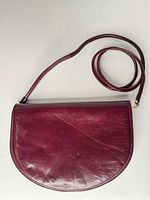 Front view of burgundy leather half-moon bag with strap