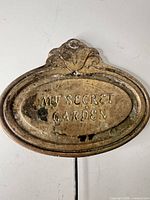 Front view of oval plaque showing raised text and patina