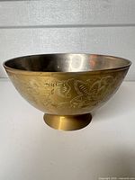 Side view showing engraved floral design on brass bowl with silver interior