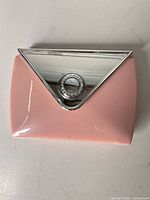 closed compact front showing pink body and silver triangular lid