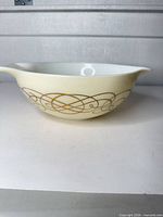 Side view showing cream milk glass body and gold scroll design