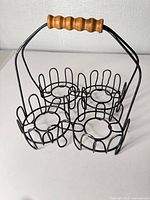 Full view of black wire carrier showing wooden handle and four compartments