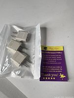 Three plug adapters in clear plastic bag with thank you card