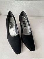Full view of both black fabric pumps showing square toe and overall condition