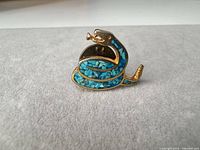 Front view of snake brooch showing turquoise chip inlay and gold-tone finish