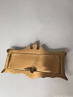 Front view of brass mail slot cover showing overall shape and hinged flap
