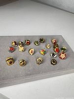 Full group of 19 AMA enamel pins laid out on fabric