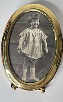 Front view of oval brass picture frame with child portrait