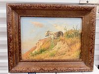 Frontal view of framed painting showing donkey on hill scene