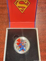 Coin in open inner case showing colored Superman design