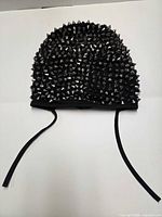 Mask exterior laid flat showing dense silver cone studs and ties