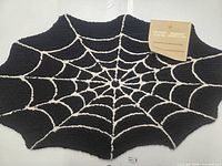 Full view of spider web shaped rug with tag attached