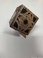 Puzzle box on stand showing etched brass-style pattern