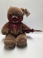 Full view of teddy bear showing blood detailing, teeth, dagger, hang tag