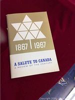 Photo of the front cover of the cookbook showing the title 'A Salute To Canada A Review Of The Century' with a design of a geometric maple leaf and the years 1867 and 1967.