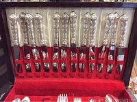 Utensils displayed in open double chest with red felt lining, knife handles visible