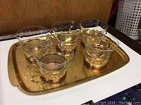 Eleven-piece copper European tea set arranged on the tray showing six glass cups with copper holders.