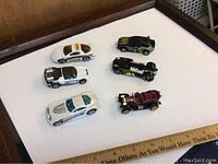 Top-down view of the 6 toy cars arranged on a white surface showing their variety in colors and styles.