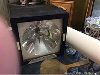 Front view showing black square casing and reflective interior cone of the strobe light.