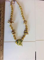 Full view of the entire 18-inch necklace showing the wooden beads and angel fish pendant next to a ruler for size reference.