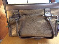 Front side view of the copper coloured jewelry travel case showing textured pattern and handles.